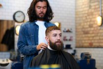 Hairdresser putting protective cape — Stock Photo