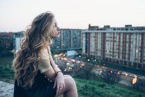 Молодая женщина сидит на крыше — стоковое фото