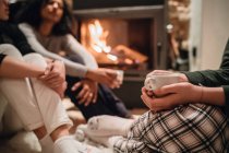 Friends in front of fire drinking coffee — Stock Photo