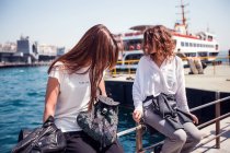 Tourists sitting at harbour by passenger ferry — Stock Photo