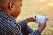 Мальчик играет в игру на сотовом телефоне — стоковое фото
