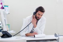 Doctor at desk making telephone call — Stock Photo