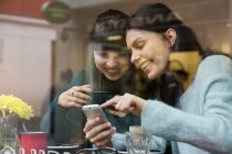 Дві молоді жінки дивляться на смартфон — стокове фото