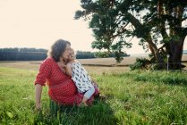 Donna seduta in campo con figlia — Foto stock