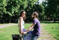 Woman on handlebars of boyfriend bicycle in park — Stock Photo