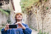 Mature woman photographing from cobbled street — Stock Photo