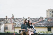Couple sitting on wall pointing — Stock Photo