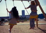 Friends swinging on playground swing — Stock Photo