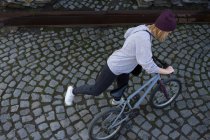 Молода жінка монтує велосипед BMX — стокове фото