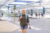 Zaino in spalla femminile a piedi nella stazione degli autobus — Foto stock