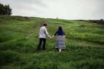 Couple walking up grassy hill — Stock Photo