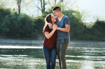 Casal romântico em pé ao lado do rio — Fotografia de Stock