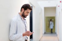 Medico in ospedale guardando il telefono cellulare — Foto stock