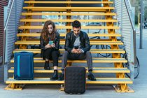 Couple using mobile phone on steps — Stock Photo