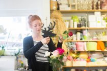 Floristería arreglando flores en la tienda - foto de stock