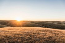 Vista da paisagem do por do sol de colinas de pradaria rolando — Fotografia de Stock