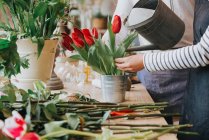 Fleuriste arrosage fleurs dans la boutique de fleurs — Photo de stock