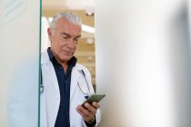 Доктор дивиться на мобільний телефон — стокове фото
