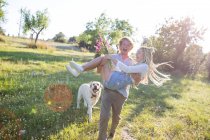 Homem se divertindo carregando namorada no campo — Fotografia de Stock