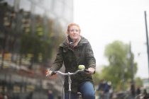 Student cycling away from University Library — Stock Photo