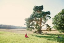 Вагітна жінка сидить у полі — стокове фото