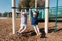 Boy and girl hanging from climbing frame — Stock Photo