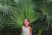 Preteen girl in front of frond palm — Stock Photo