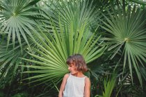 Preteen girl in front of frond palm tree — Stock Photo