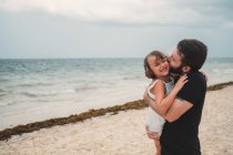 Отец целует дочь на пляже — стоковое фото