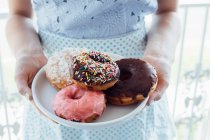 Woman holding plate of doughnuts — Stock Photo