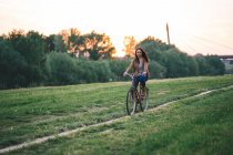 Женщина на велосипеде по траве — стоковое фото