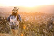 Woman hiking, wearing stars and stripes backpack, rear view — Stock Photo