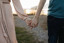Couple holding hands outdoors, mid section, close-up — Stock Photo
