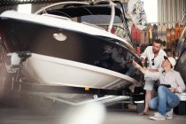 Двое мужчин проверяют кузов моторных лодок в ремонтной мастерской — стоковое фото