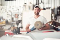Portrait of man with polishing machine in boat repair workshop — Stock Photo