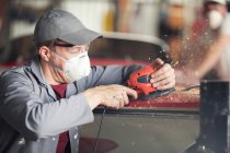 Man sanding bodywork in boat repair workshop — Stock Photo