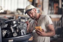 Man using machine to test outboard motor in boat repair workshop — Stock Photo