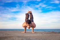 Young man outdoors, in yoga position, balancing on hands — Stock Photo