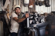 Чоловік тестує підвісний двигун у майстерні ремонту човнів — стокове фото