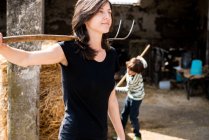 Female farmer and boy with pitch forks — Stock Photo