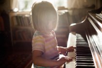 Chica tocando piano viejo - foto de stock