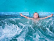 Cute boy splashing in swimming pool — Stock Photo