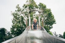 Boy at top of playground slide — Stock Photo
