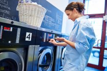 Frau steckt Münzen in Waschmaschine — Stockfoto