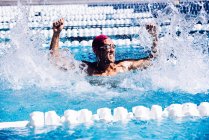 Nadador na piscina batendo água em triunfo — Fotografia de Stock