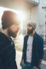 Male hipsters in knit hats in city sunlight — Stock Photo