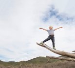 Хлопчик балансує на кінці стовбура дерева — стокове фото