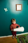 Cute male toddler rolling paper — Stock Photo