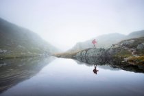 Escursionista maschio escursioni lungo la nebbiosa riva del fiume — Foto stock