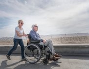 Жінка штовхає чоловіка в інвалідному візку — стокове фото